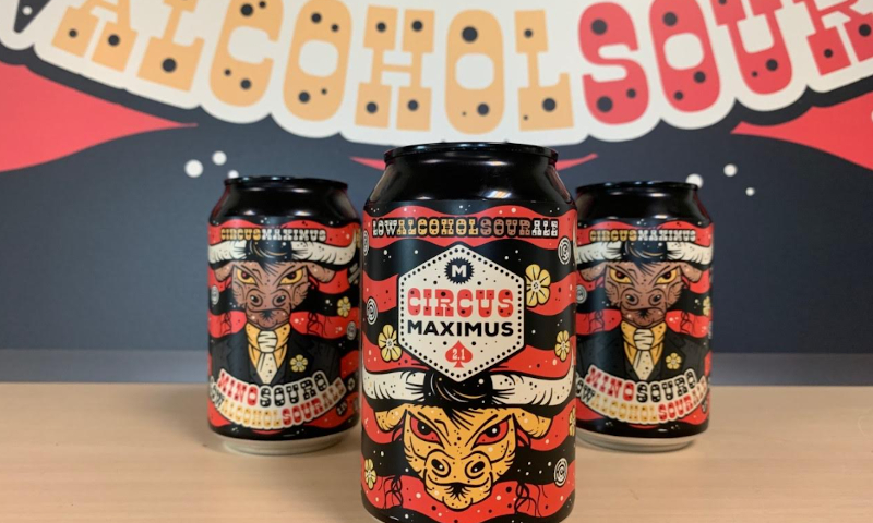 Drie blikjes Mino Souro van de Maximus Brouwerij op tafel voor een banner van het biermerk